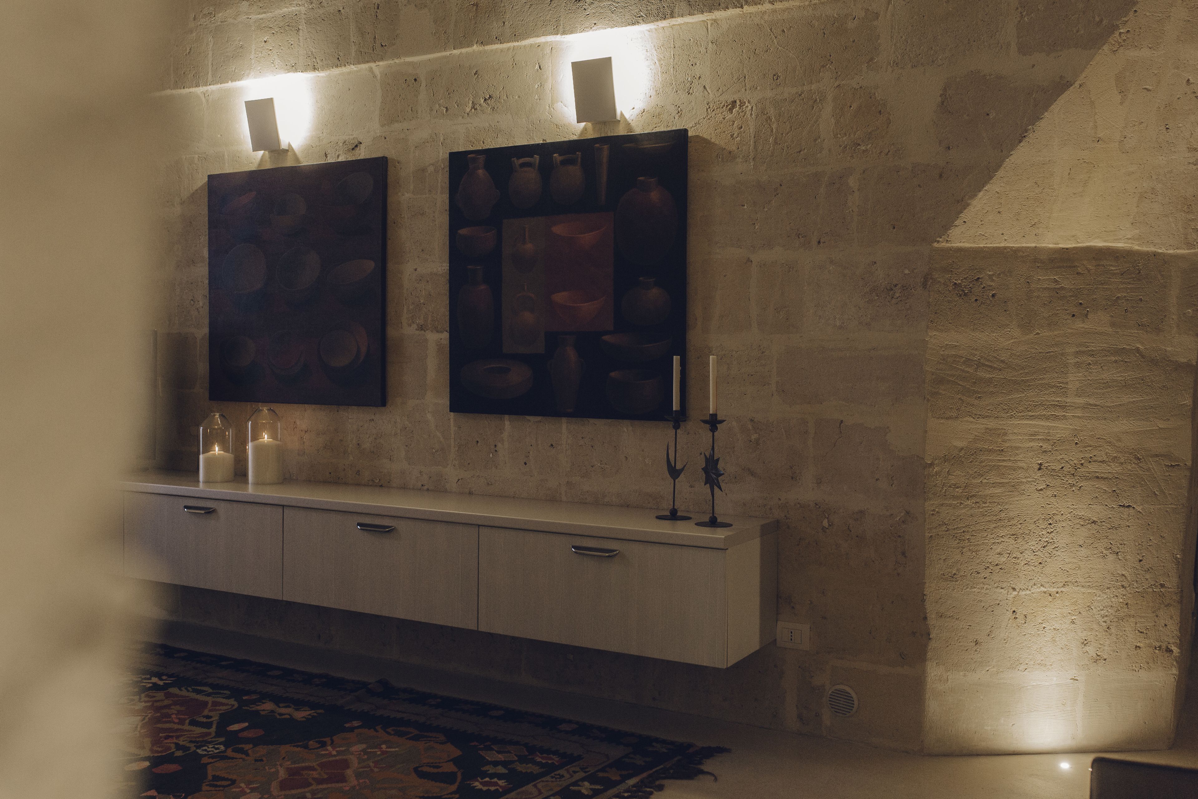 A room with a stone wall, a wooden cabinet, and two wall-mounted artworks.