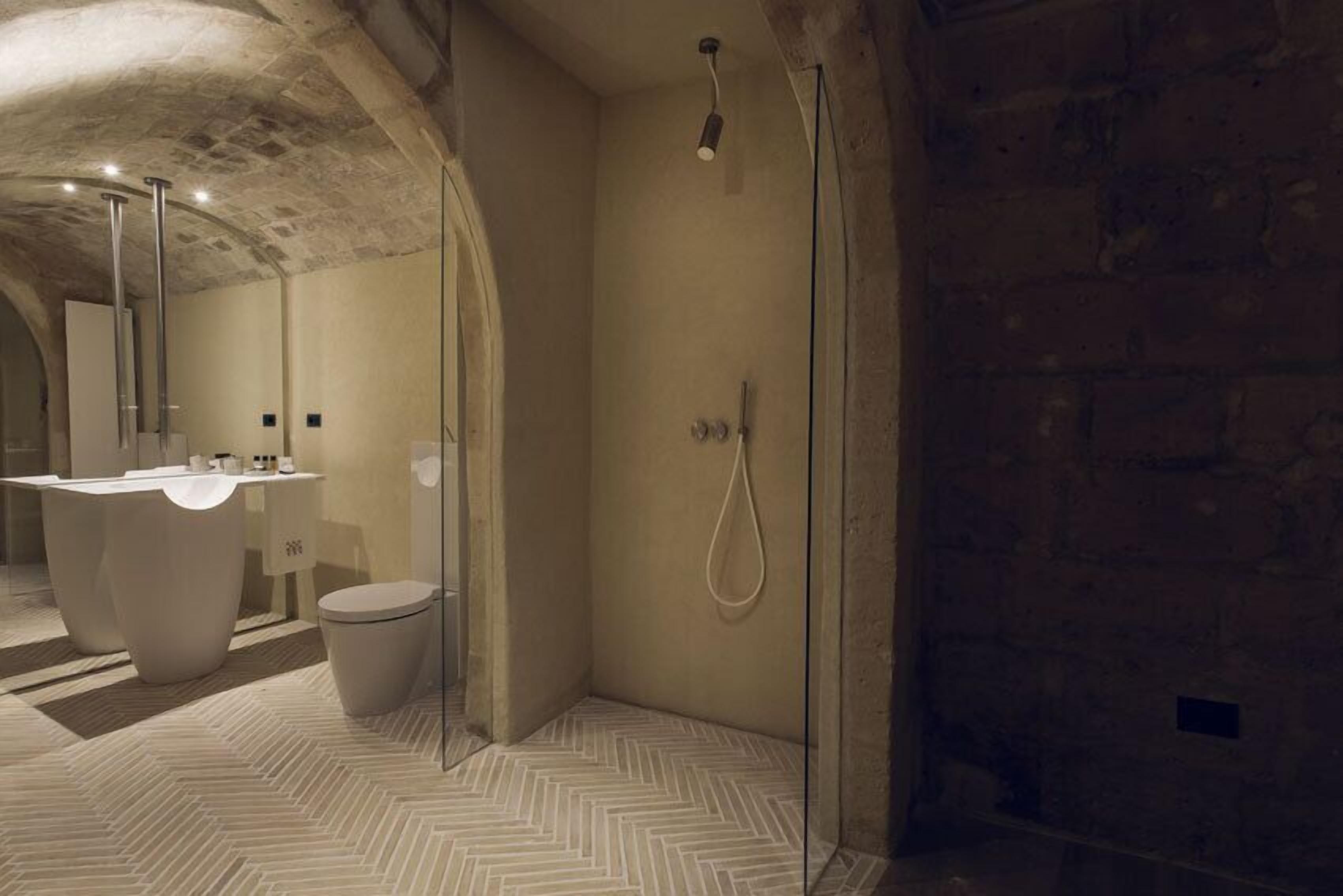 Un baño moderno con suelo de espiga, una bañera independiente, ducha con mampara de cristal y un espejo grande.