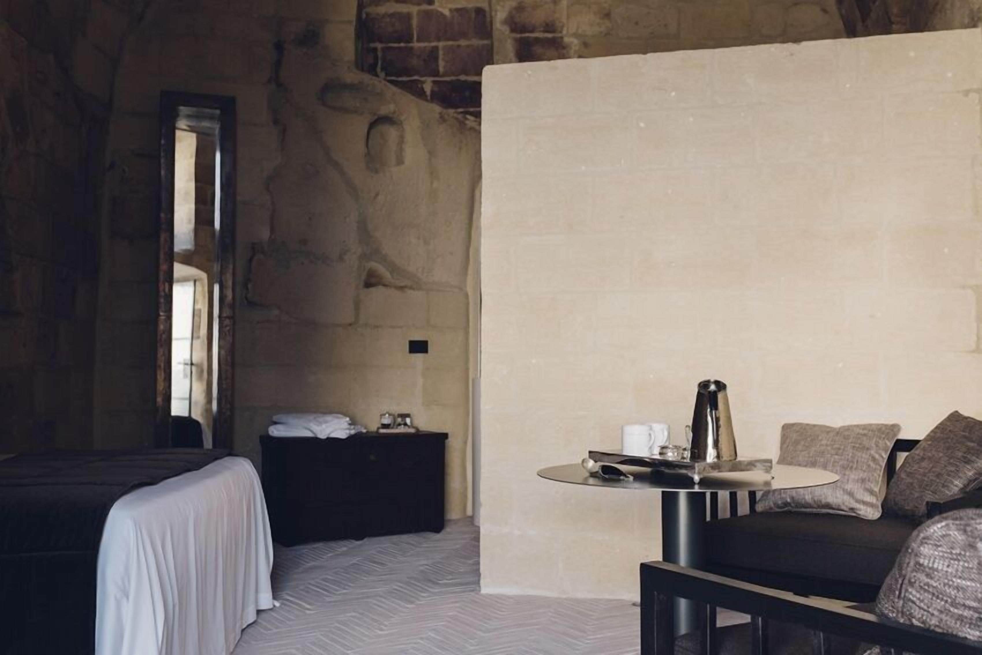 A hotel room with a bed, a small table with a kettle, and a sofa.