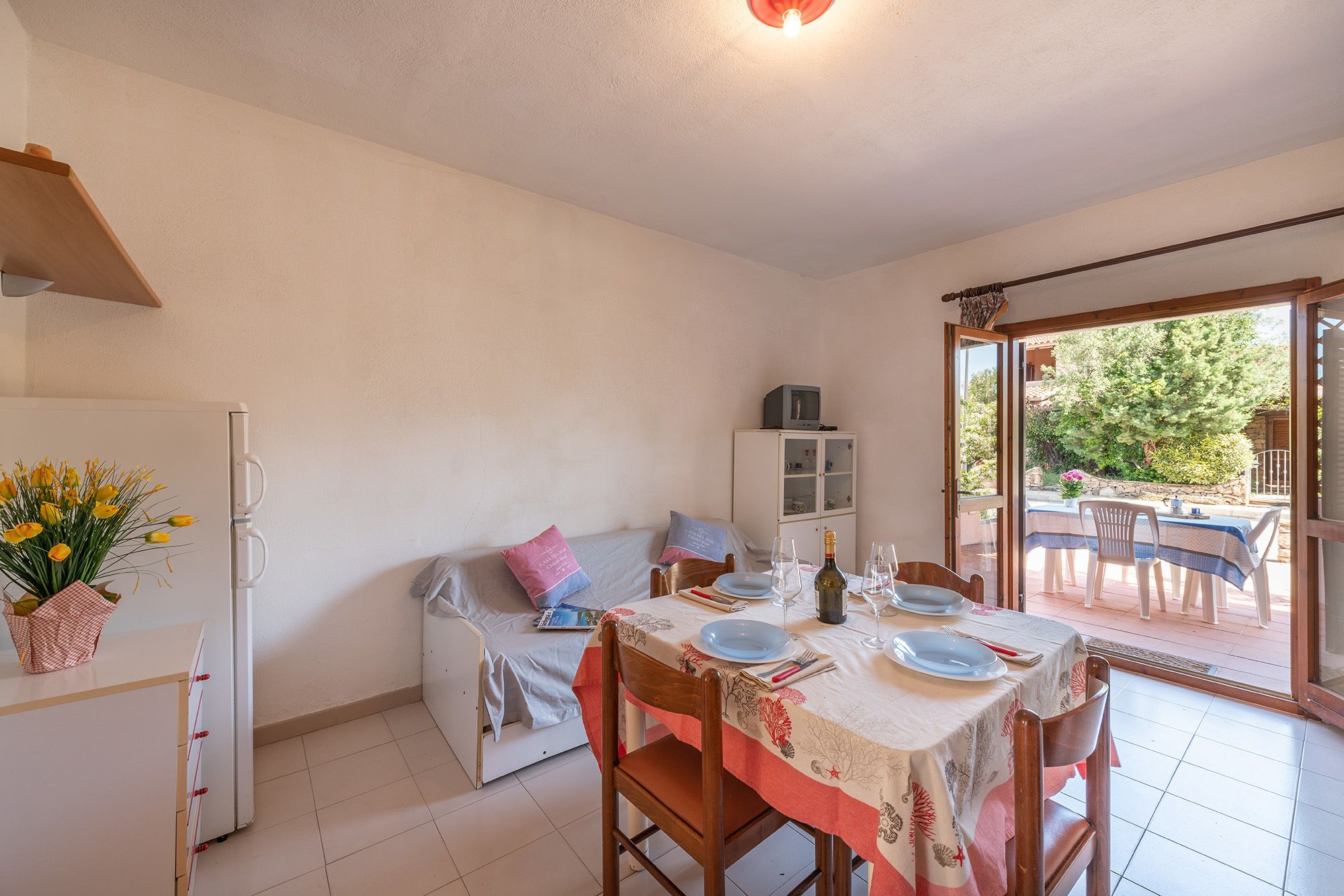 A compact kitchen with a dining area, a refrigerator, a cabinet, and a table set for two with chairs.