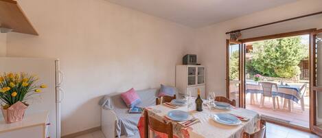 A compact kitchen with a dining area, a refrigerator, a cabinet, and a table set for two with chairs.