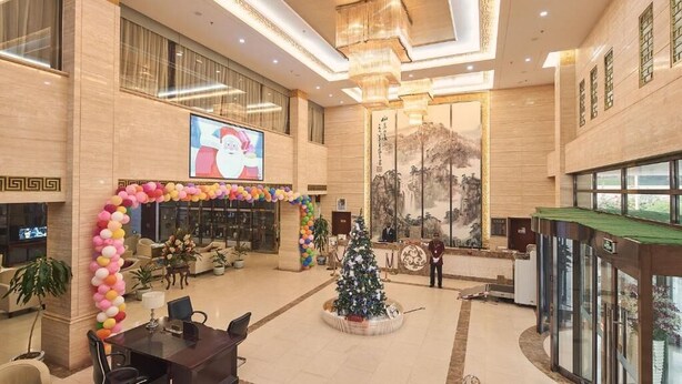 Eine geräumige Lobby mit Weihnachtsbaum, großem Bildschirm und Rezeption.