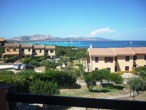 A coastal residential area with terraced houses, a clear blue sky, and a view of the sea with boats.