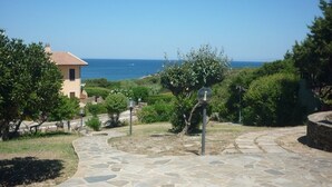 Un chemin de pierre menant à un bâtiment d’où l’on a vue sur la mer.
