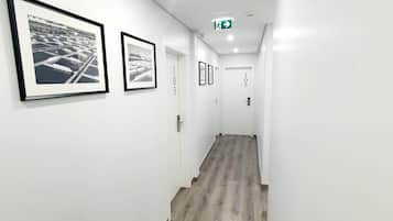 Ein Flur mit Holzboden, weißen Wänden und gerahmten Bildern.