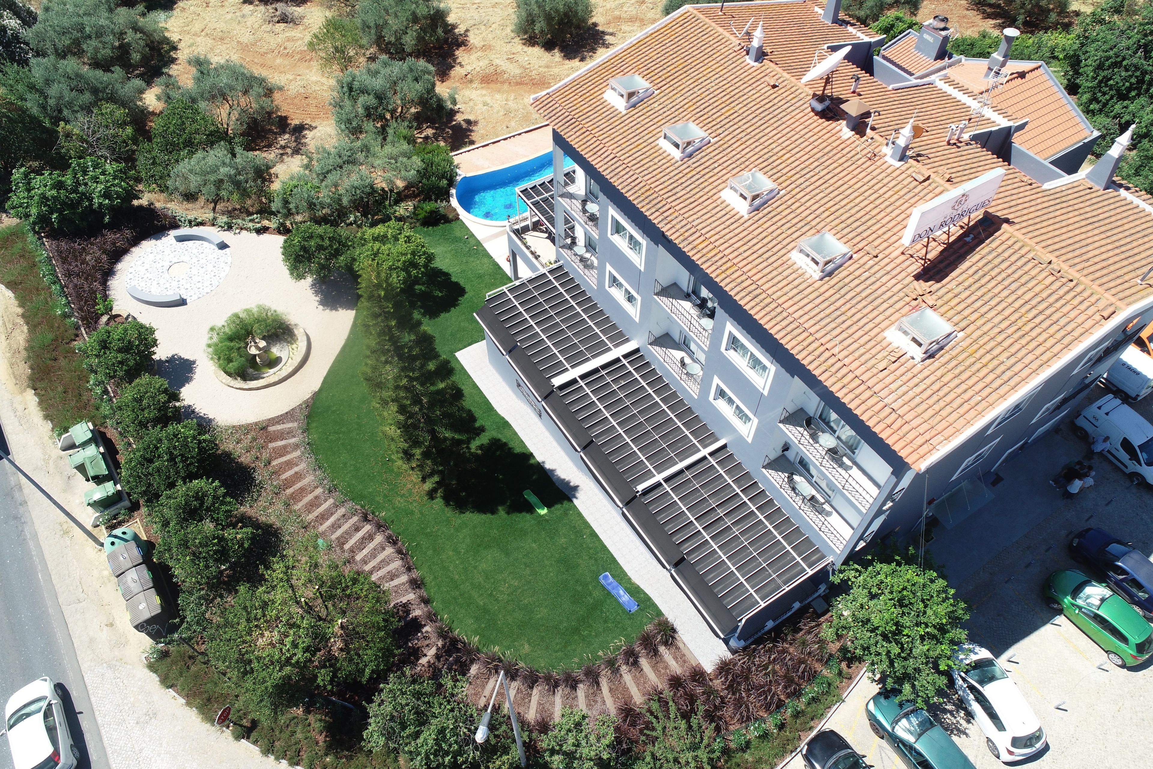 Una casa moderna de dos pisos con piscina, paneles solares y un jardín ajardinado.