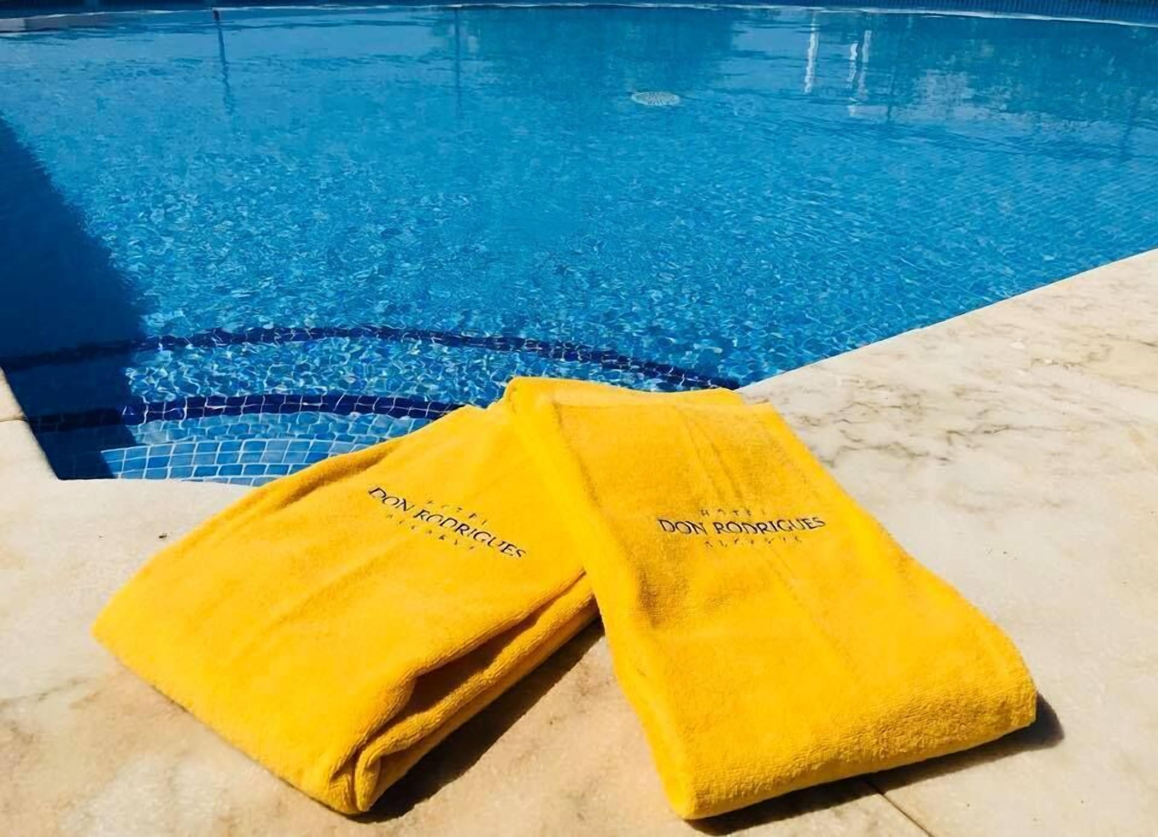 Two yellow towels with text on a poolside area.