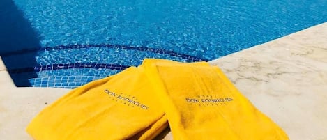 Dos toallas amarillas con texto en una zona junto a la piscina.