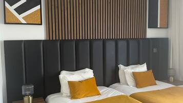 A hotel room with two beds, a wooden slat headboard, a modern abstract painting, and a bedside table with a lamp.