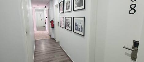 A hallway with a wooden floor, white walls, and numbered doors.