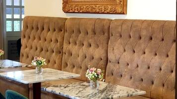 A seating area with a tufted brown sofa, a marble table, and a green chair.