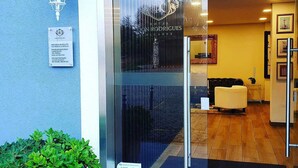 The entrance of Hotel Don Rodrigues Algarve with a glass door, a reception desk inside, and a small outdoor seating area visible through the glass. - Hotel Don Rodrigues (Tavira)
