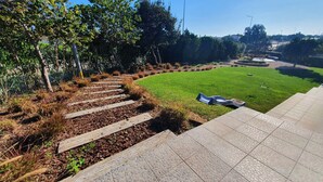 A park with a paved walkway, a grassy area, and a blue slide. - Hotel Don Rodrigues (Tavira)