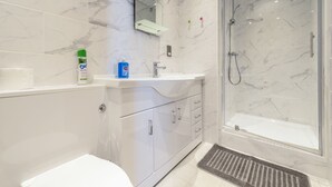 A modern bathroom with a marble sink, a toilet, and a shower area. - Piccadilly Gardens (Manchester)