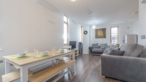 A modern living room with a dining area, a grey sofa, and a TV. - Piccadilly Gardens (Manchester)