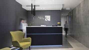 A modern reception area with a dark reception desk, a yellow armchair, and a black pendant light.