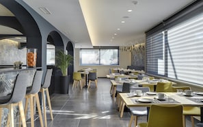 A modern dining area with high ceilings, large windows, and a mix of seating arrangements.