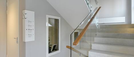 A modern staircase with glass railings and wooden steps leading to multiple floors.
