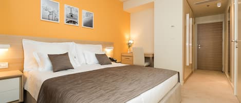 A hotel room with a large bed, bedside tables, a desk, and a wardrobe.