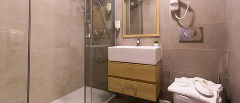 Ein modernes Badezimmer mit Duschkabine aus Glas, Waschbecken mit Spiegel darüber und Toilette mit Handtuchhalter.