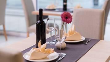 A dining table set with a bottle, wine glass, and a flower arrangement.