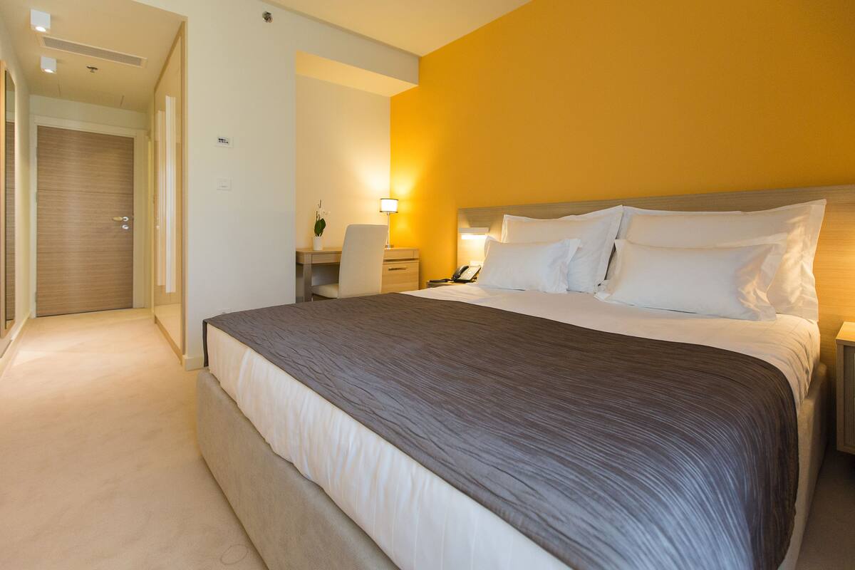 Een hotelkamer met een groot bed, nachtkastjes, een bureau en een stoel.