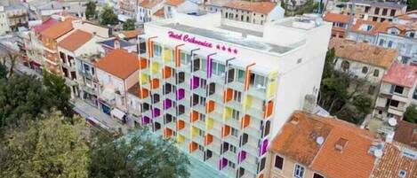 A multi-story hotel with balconies, surrounded by a densely packed urban area with various buildings.