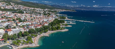 Vista aérea de un pueblo costero con puerto deportivo, playa y edificios residenciales.