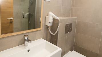 Un baño moderno con lavamanos, espejo y retrete blancos.