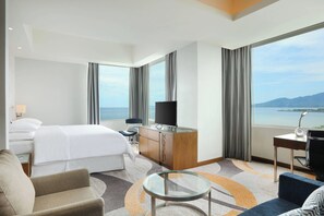 A hotel room with a bed, a desk, a chair, a TV, and a view of the sea. - Four Points by Sheraton Manado (Manado)