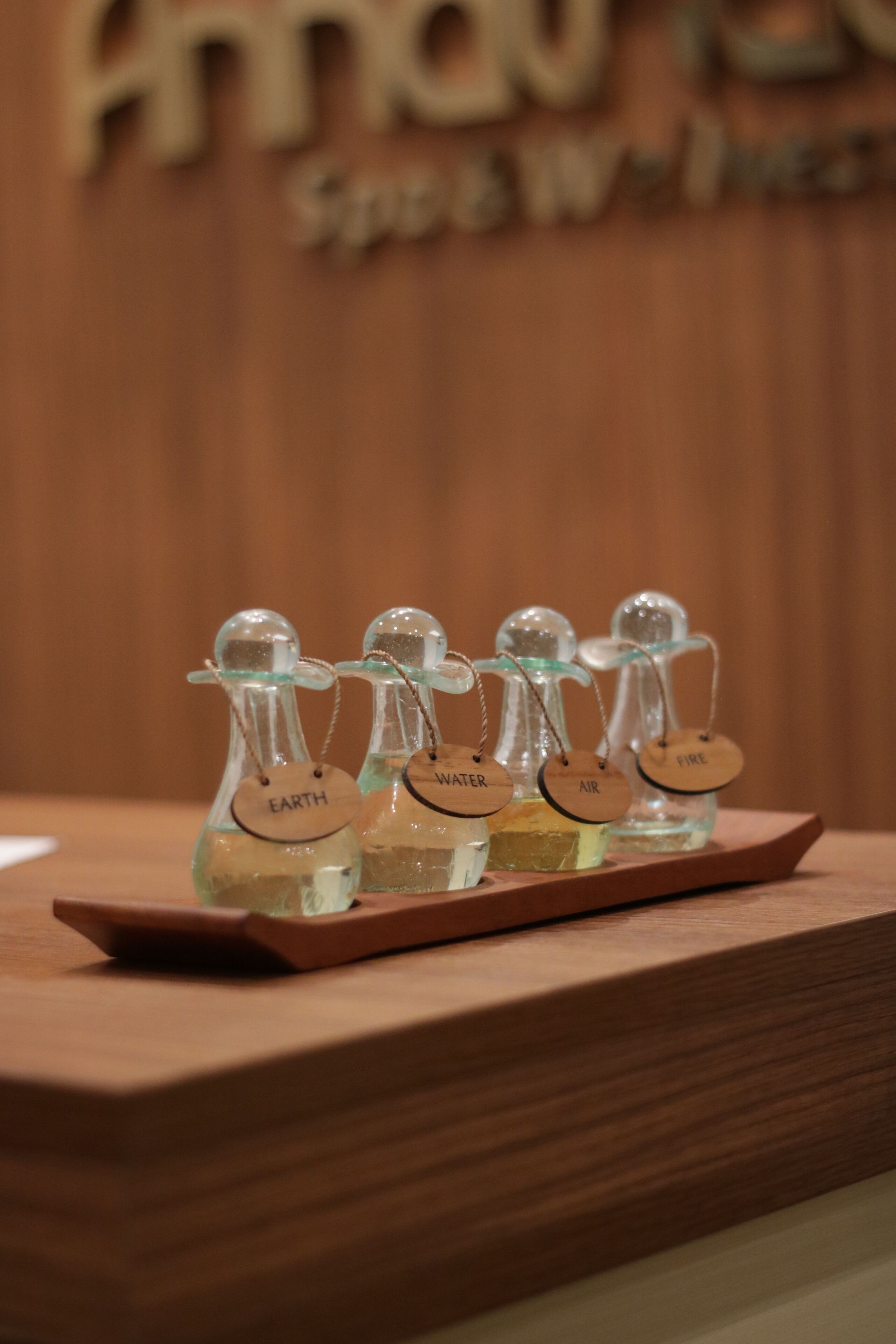 A wooden tray with four glass bottles labeled 'EARTH,' 'WATER,' 'AIR,' and 'FIRE.'