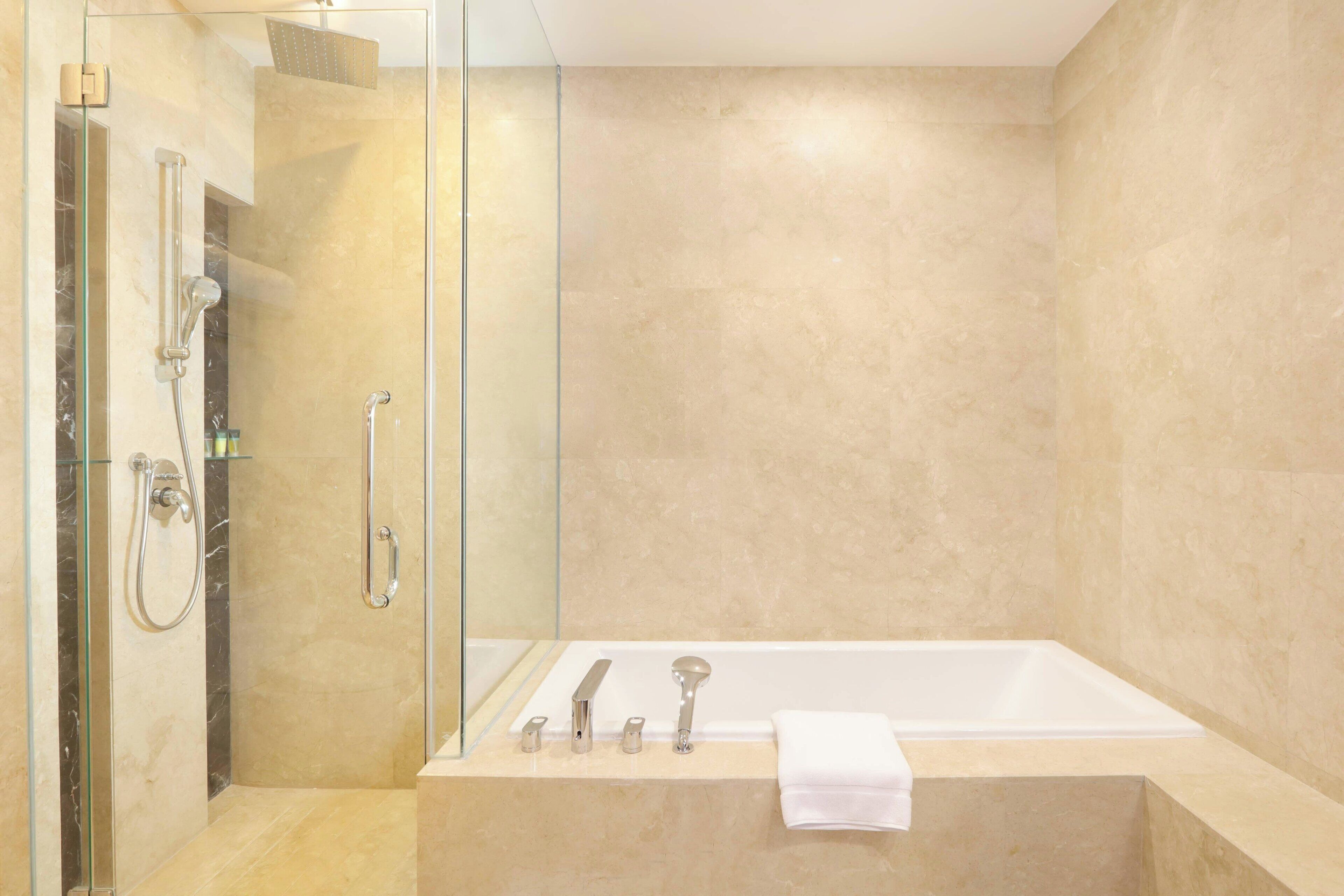 A modern bathroom with a glass-enclosed shower, a bathtub, and a glass shower door.