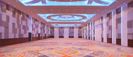 A hotel corridor with a patterned carpet, recessed lighting, and a modern ceiling design.