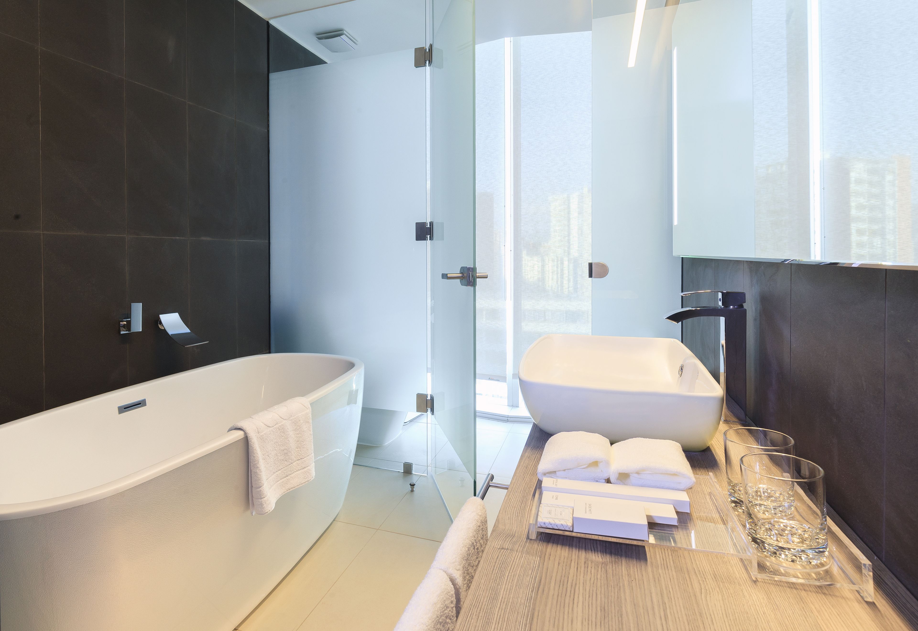 A modern bathroom with a freestanding bathtub, a large mirror, and a glass shower enclosure.