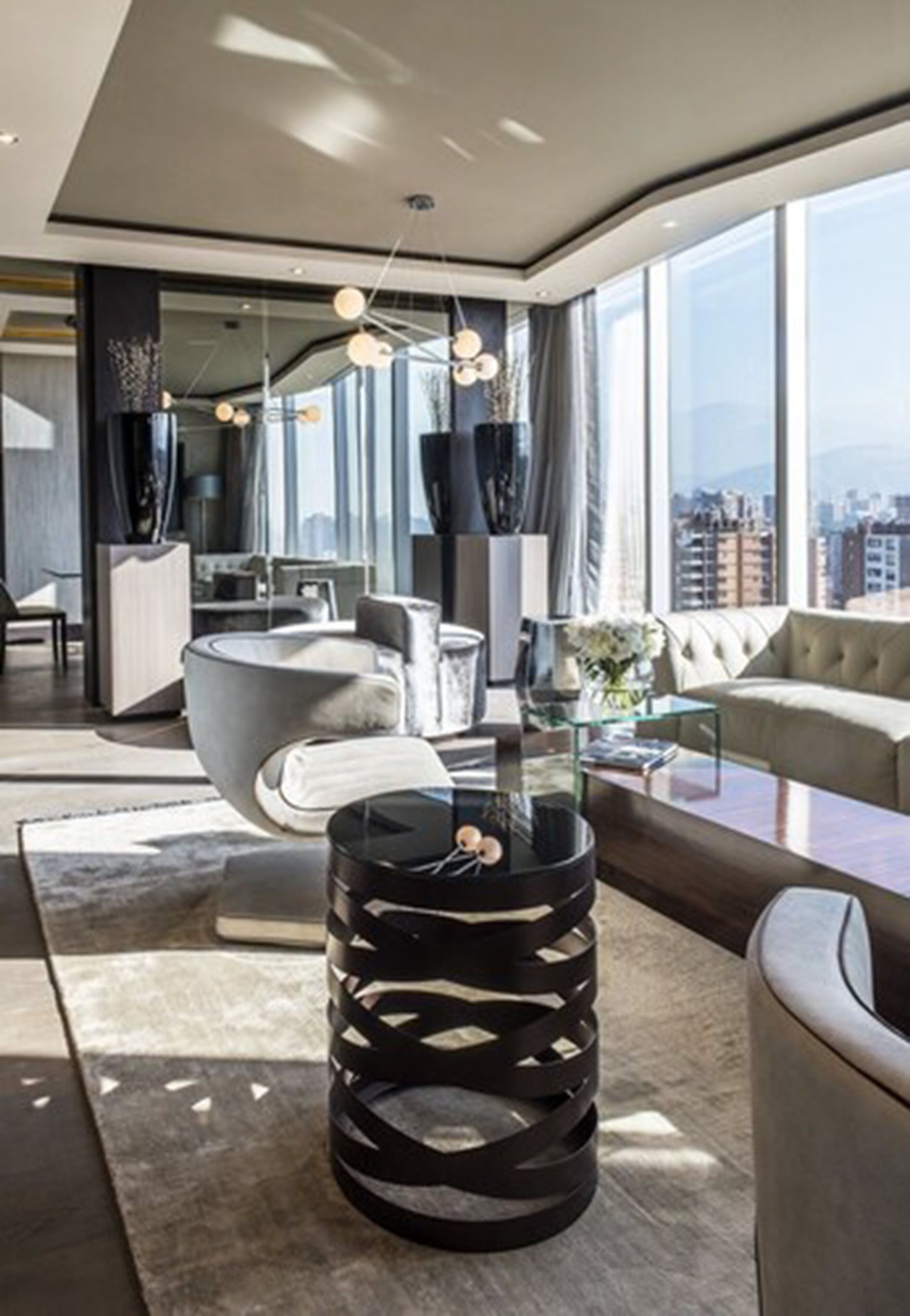 A modern living room with a large window, a round black table, and a sofa.