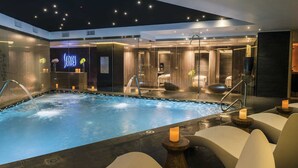 Área interna de piscina moderna, com vista clara da piscina, espaços para sentar e um balcão de recepção.