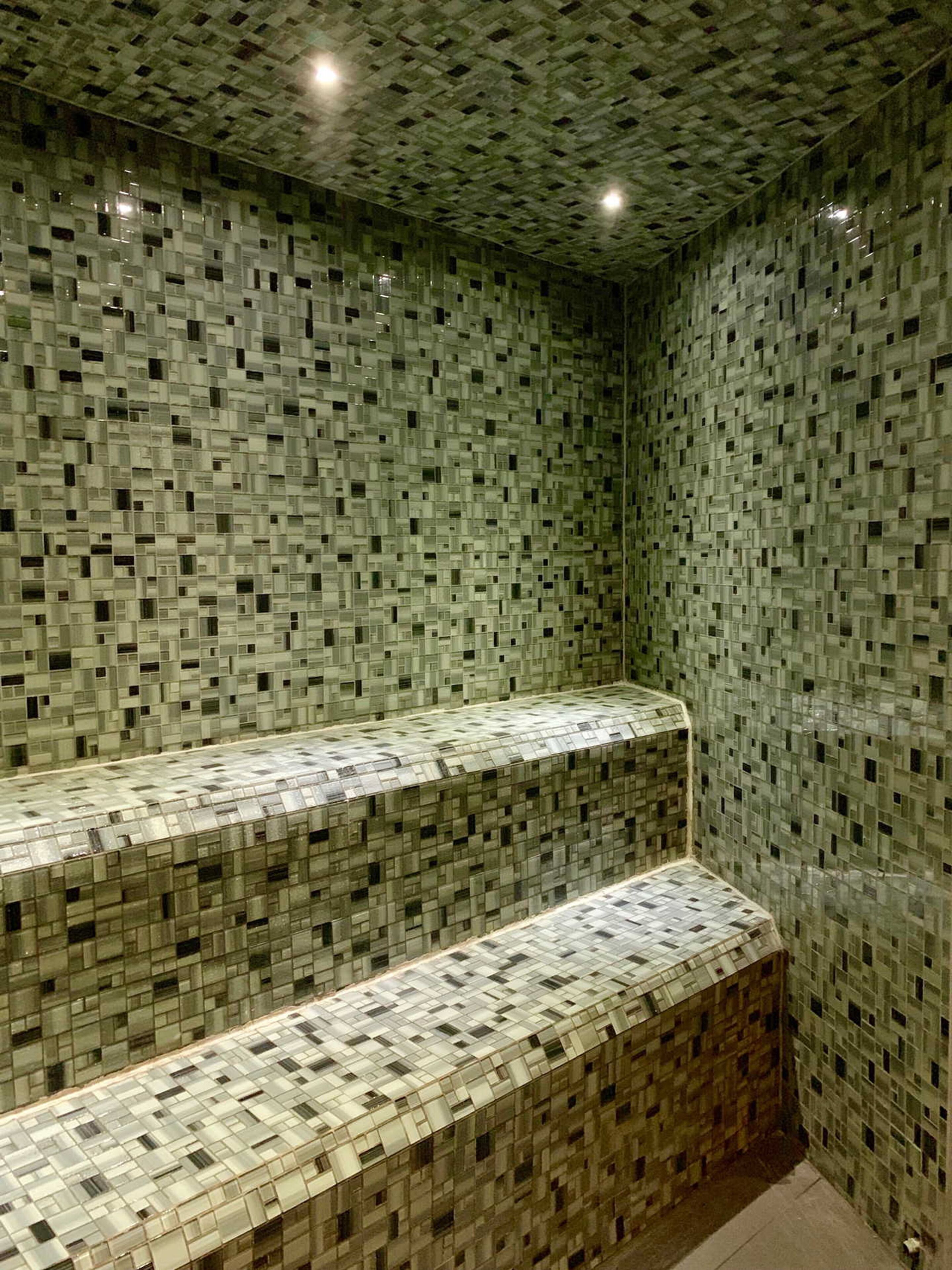 A room with a patterned tiled wall and a built-in bench.