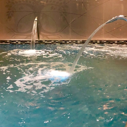A pool with water jets, a tiled border, and a visible crack in the wall.