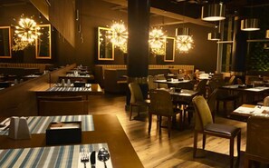 Enjoy dining in a warm and inviting space with tables set for a meal, surrounded by artwork and soft lighting.