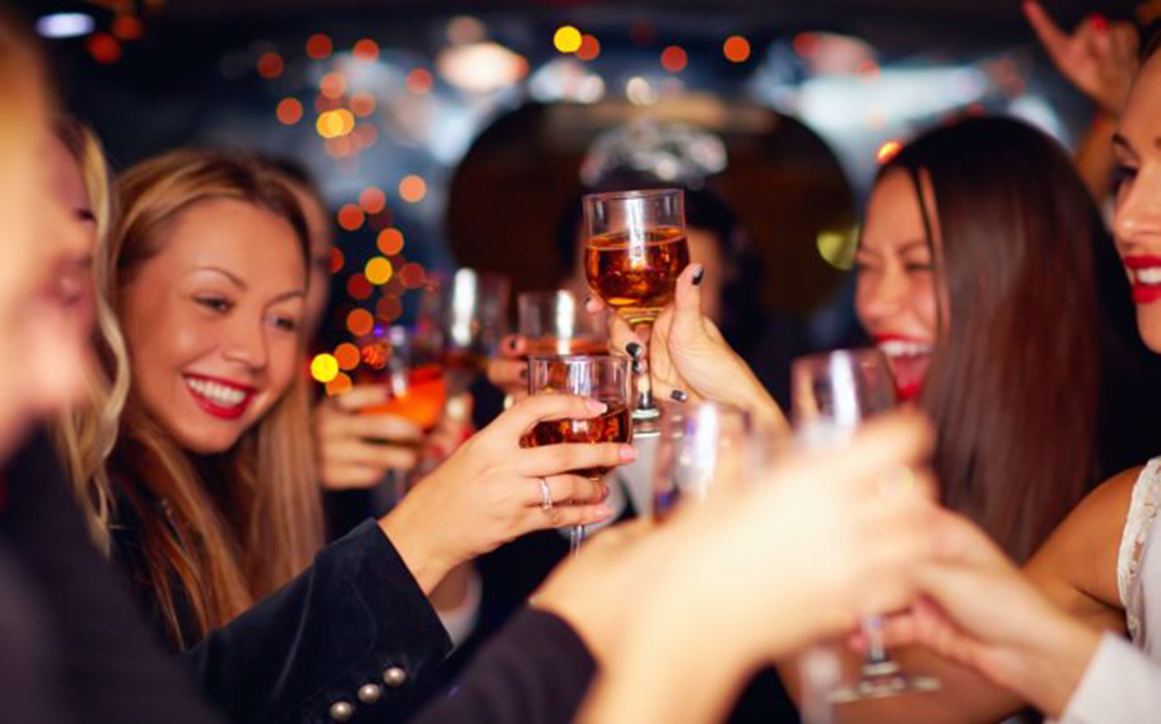 A group of people toasting with drinks in a dimly lit setting.