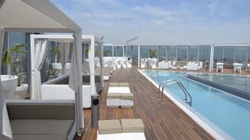 Una piscina techada, una piscina al aire libre, sombrillas