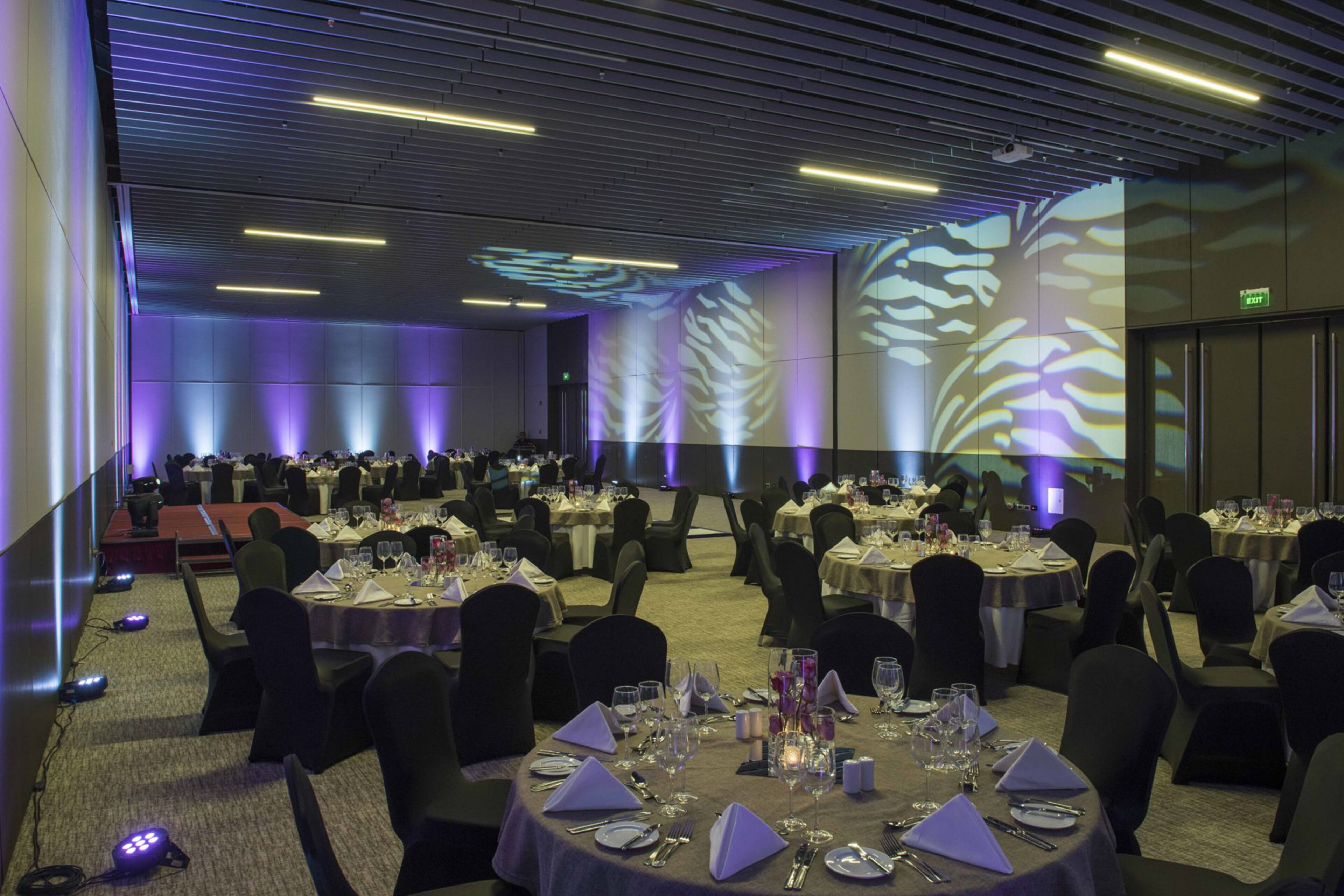 A banquet hall with round tables set for dining, equipped with chairs, tablecloths, and table settings.