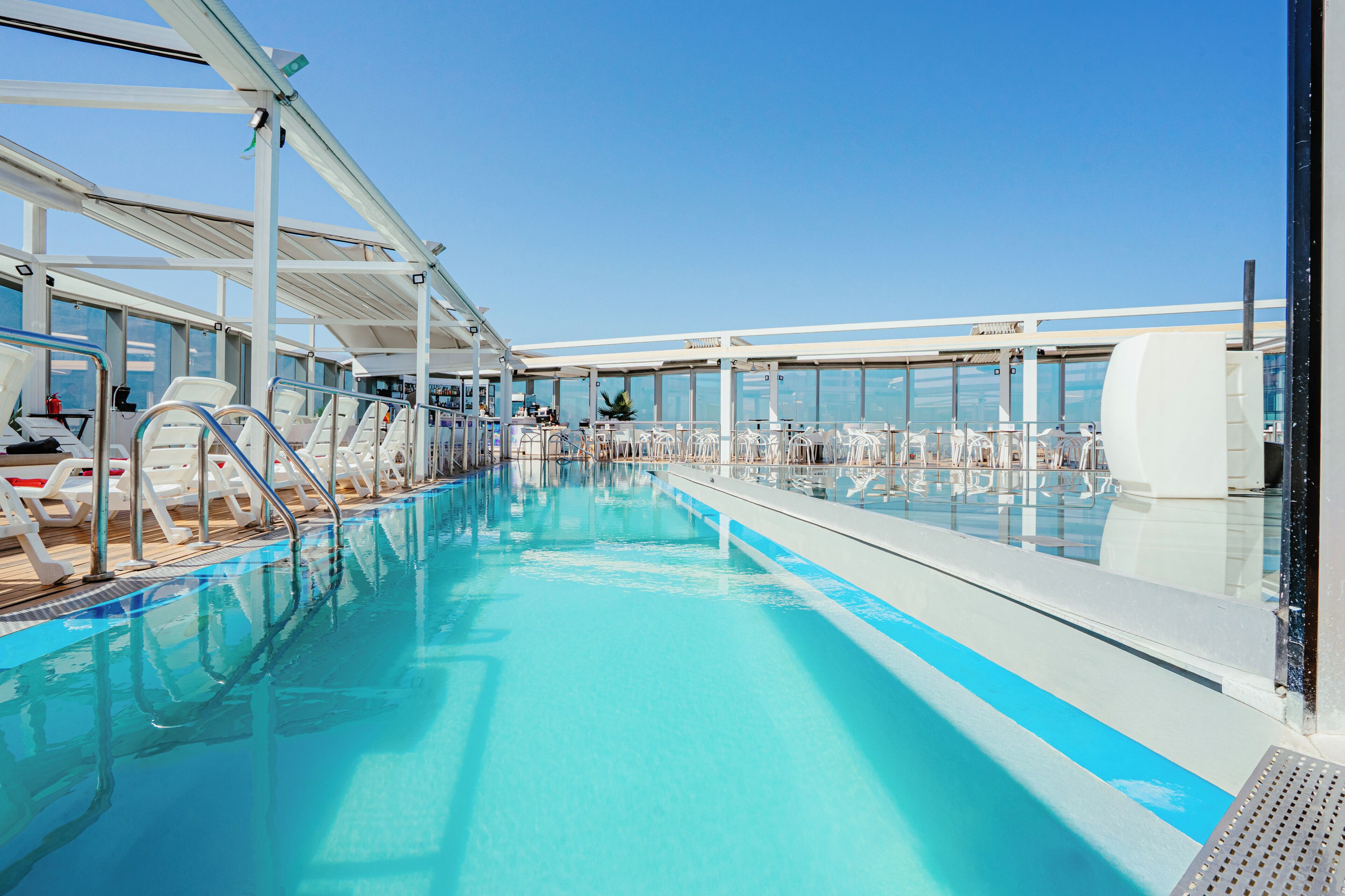 Una piscina techada, una piscina al aire libre, sombrillas