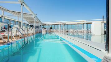Una piscina techada, una piscina al aire libre, sombrillas
