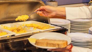 Montaje de bufé con platos etiquetados y un letrero que indica 'Huevos Rellenos Con Salsa'.