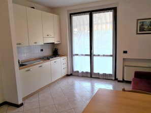A kitchen with white cabinets, a tiled floor, and a sliding glass door.