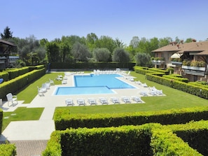 A rectangular swimming pool with lounge chairs and a well-manicured lawn.