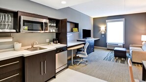 A modern kitchen with built-in appliances, a dining area, and a seating space. - Home2 Suites by Hilton Stafford Quantico (Stafford)