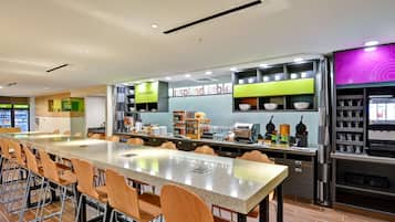 A modern restaurant with a long counter, bar stools, and a variety of food and drink stations.