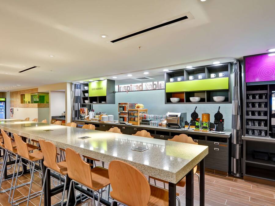 A modern restaurant with a long counter, bar stools, and a variety of food and drink stations.